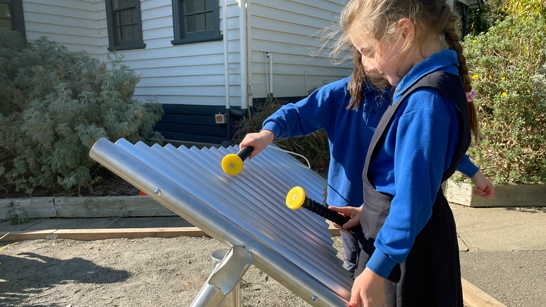 Two young school students playing wellbeing instruments' outdoor musical instrument "Composer" in a school yard.